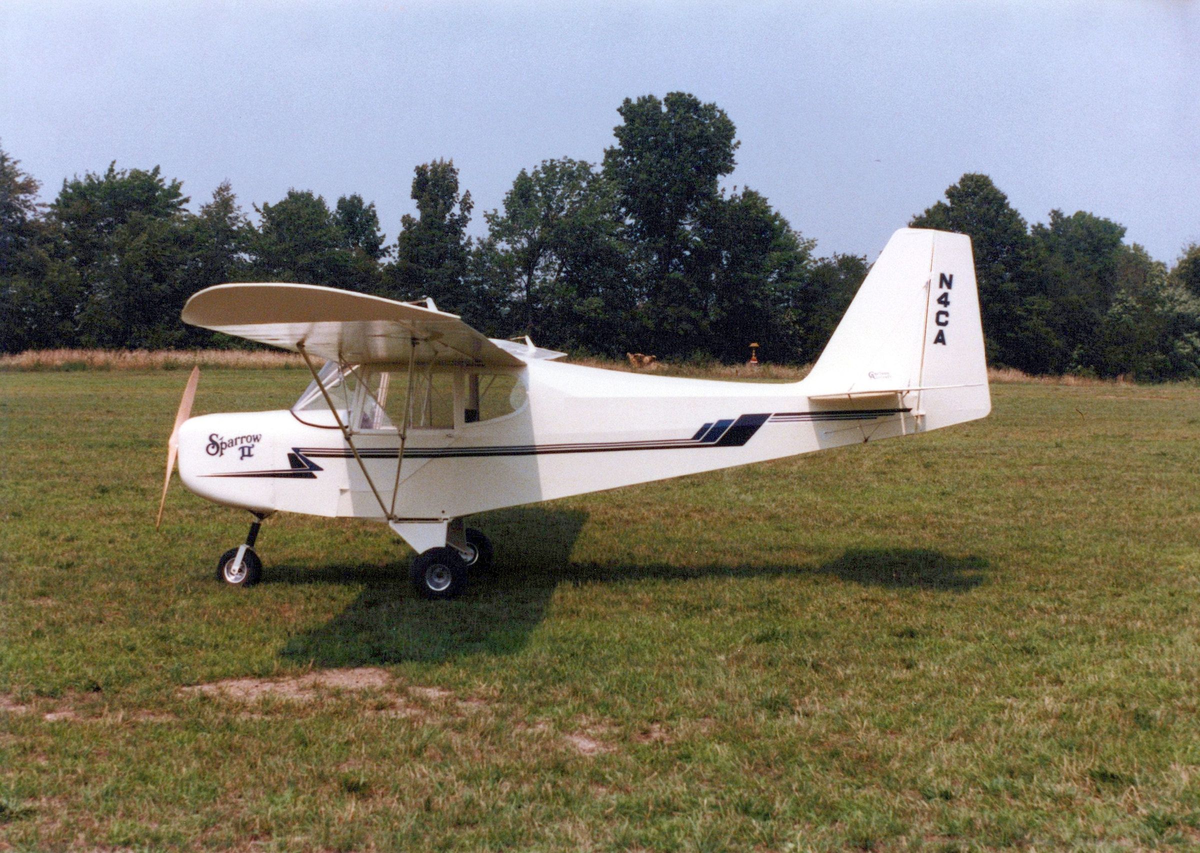Side view of a white Carlson Sparrow II with tricycle landing gear on a grass field